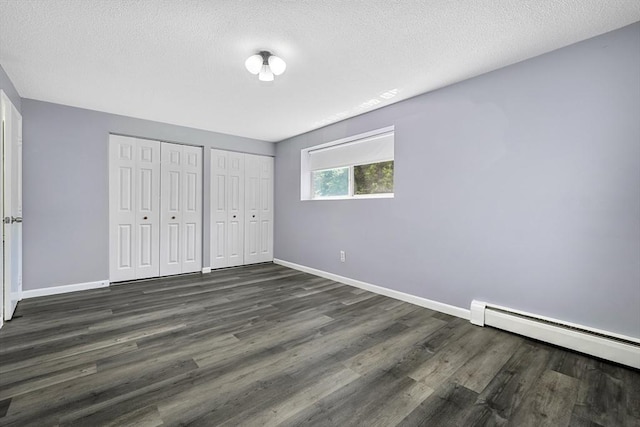64 Main St Unit 25B, Stoneham, MA 02180 - unfurnished bedroom with multiple closets, a baseboard radiator, dark wood-style flooring, and a textured ceiling