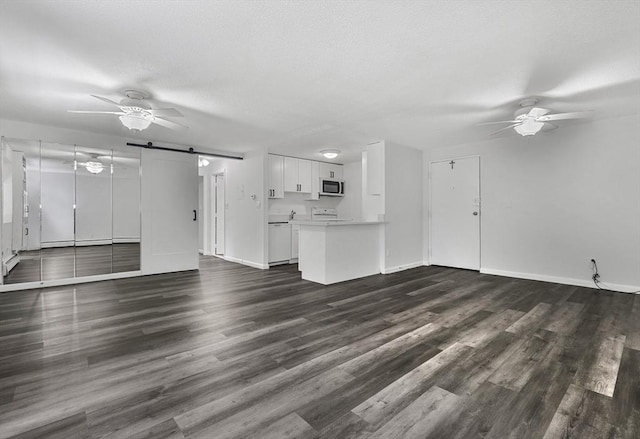 64 Main St Unit 25B, Stoneham, MA 02180 - unfurnished living room with a barn door, a ceiling fan, and dark wood-style floors