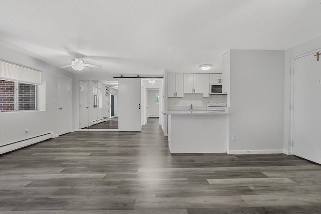 64 Main St Unit 25B, Stoneham, MA 02180 - kitchen featuring white microwave, a barn door, ceiling fan, stove, and white cabinets