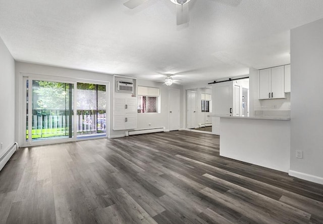 64 Main St Unit 25B, Stoneham, MA 02180 - unfurnished living room with ceiling fan, baseboard heating, a barn door, dark wood-type flooring, and a textured ceiling