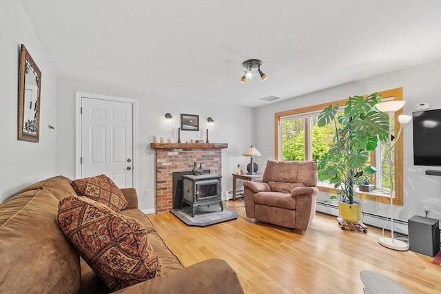 17 Lantern Ln, Leominster, MA 01453 - living area featuring a baseboard heating unit, wood finished floors, and a wood stove