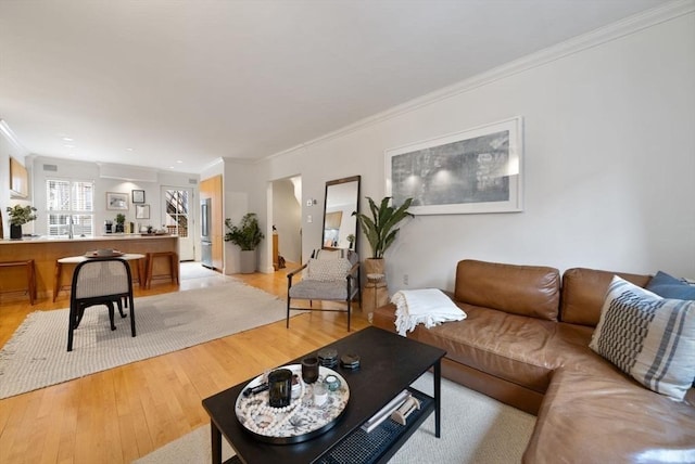 living area featuring light wood-style floors and crown molding