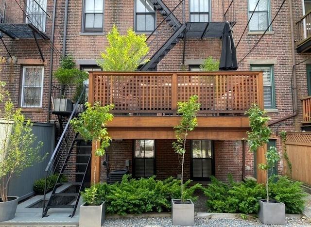 rear view of house featuring a wooden deck, fence, stairway, and brick siding