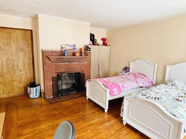 bedroom with crown molding, a fireplace, and wood finished floors