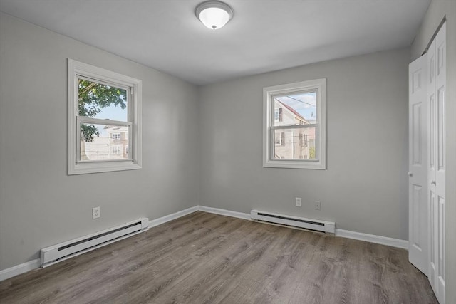 unfurnished bedroom featuring light wood-type flooring, baseboard heating, and a closet