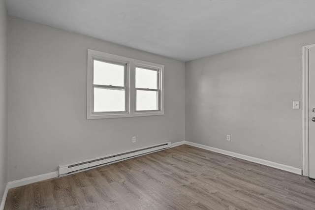 empty room with baseboard heating and light hardwood / wood-style flooring