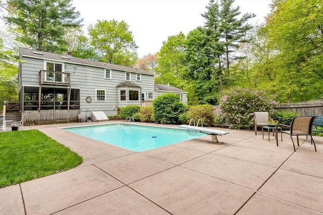 swimming pool with a patio, fence, and a diving board
