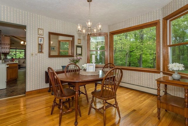 dining space with wallpapered walls, light wood-style floors, healthy amount of natural light, a chandelier, and a textured ceiling