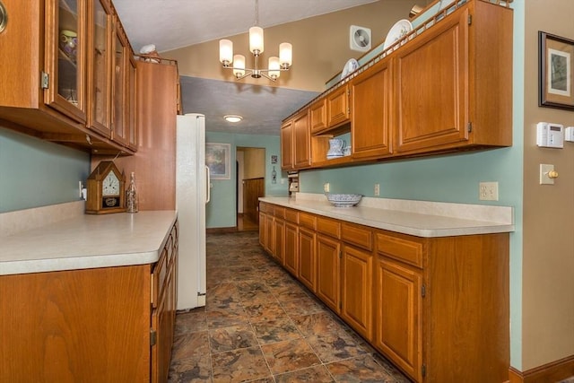 kitchen featuring brown cabinets, a chandelier, light countertops, glass insert cabinets, and stone finish floors