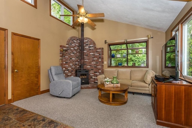 living area with a ceiling fan, a wood stove, and high vaulted ceiling