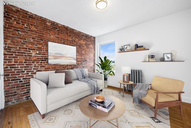 living room featuring brick wall, hardwood / wood-style floors, and radiator heating unit