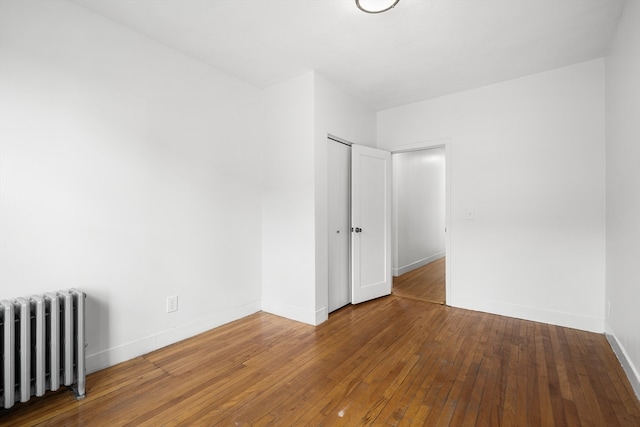 empty room featuring radiator heating unit and hardwood / wood-style floors