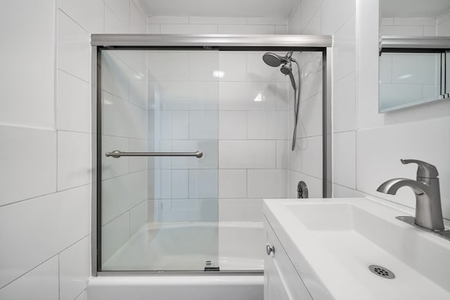 bathroom featuring combined bath / shower with glass door and vanity