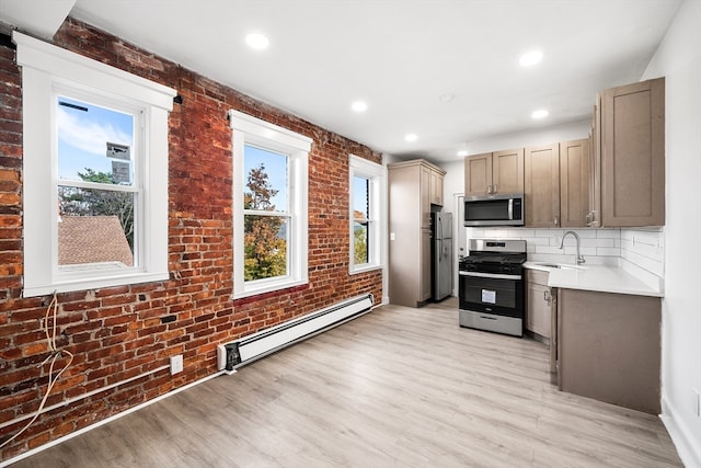 kitchen featuring brick wall, stainless steel appliances, a baseboard radiator, and sink