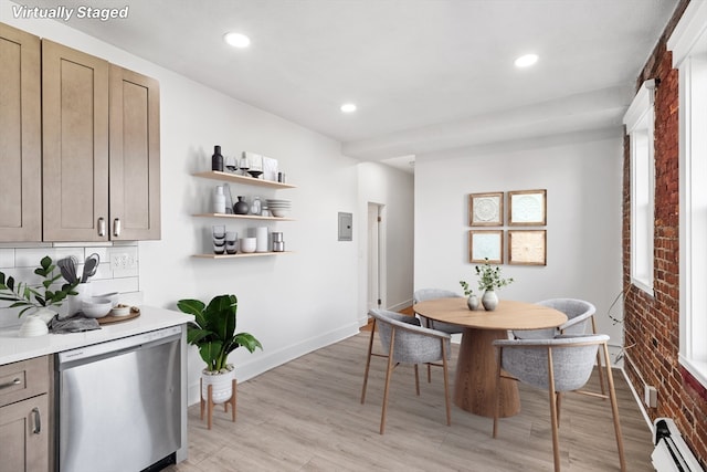 dining space with light wood-type flooring, brick wall, and a baseboard heating unit