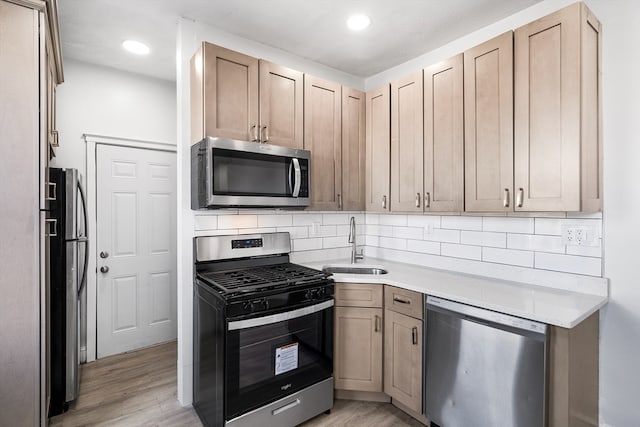 kitchen featuring appliances with stainless steel finishes, light hardwood / wood-style floors, tasteful backsplash, and sink