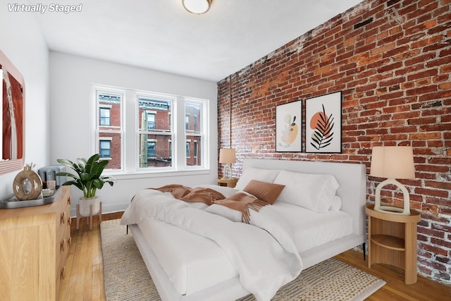 bedroom featuring brick wall and hardwood / wood-style floors