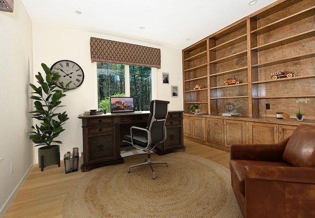 office with light wood finished floors, built in shelves, baseboards, and recessed lighting