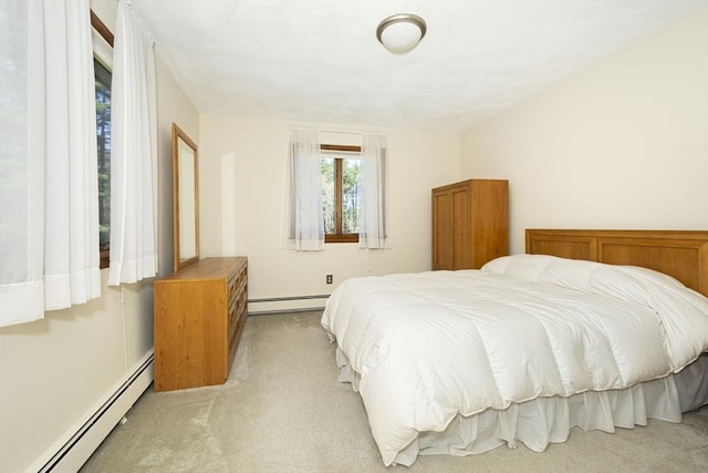 bedroom featuring a baseboard heating unit and light colored carpet