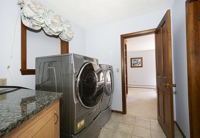 clothes washing area featuring washing machine and clothes dryer, baseboard heating, light colored carpet, baseboards, and light tile patterned floors