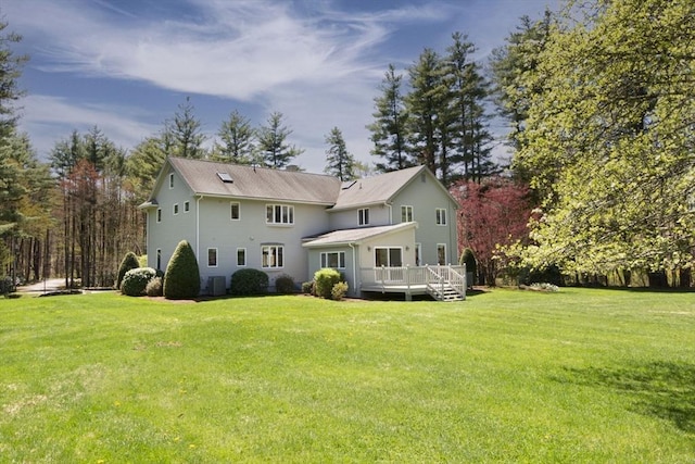 back of property with a deck and a lawn