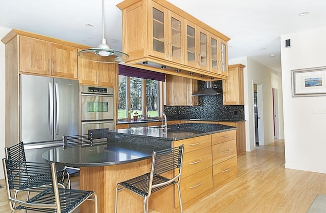 kitchen featuring appliances with stainless steel finishes, light wood-type flooring, decorative backsplash, glass insert cabinets, and recessed lighting