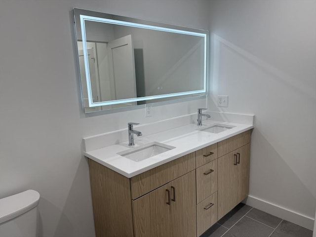bathroom featuring tile patterned flooring, double vanity, a sink, and toilet