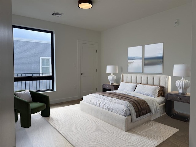 bedroom with wood finished floors, baseboards, and visible vents