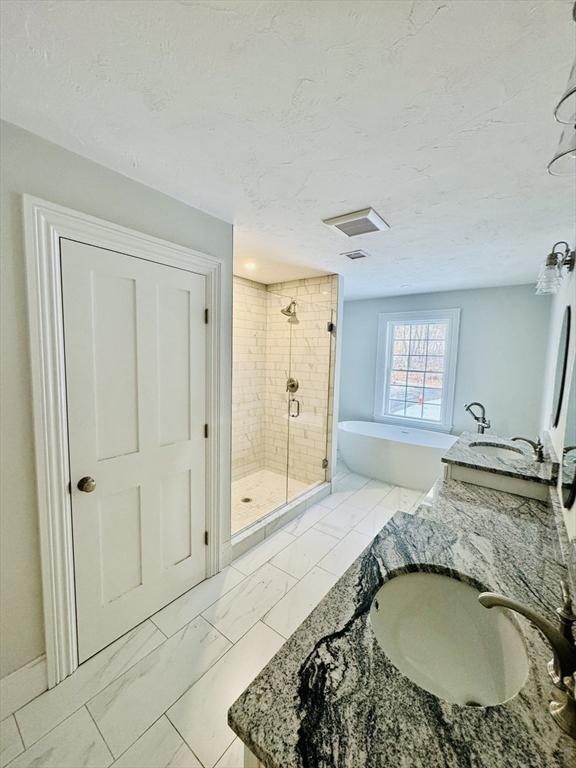 200A Randall Rd, Berlin, MA 01503 - bathroom featuring a shower stall, a soaking tub, a textured ceiling, vanity, and marble look tile flooring