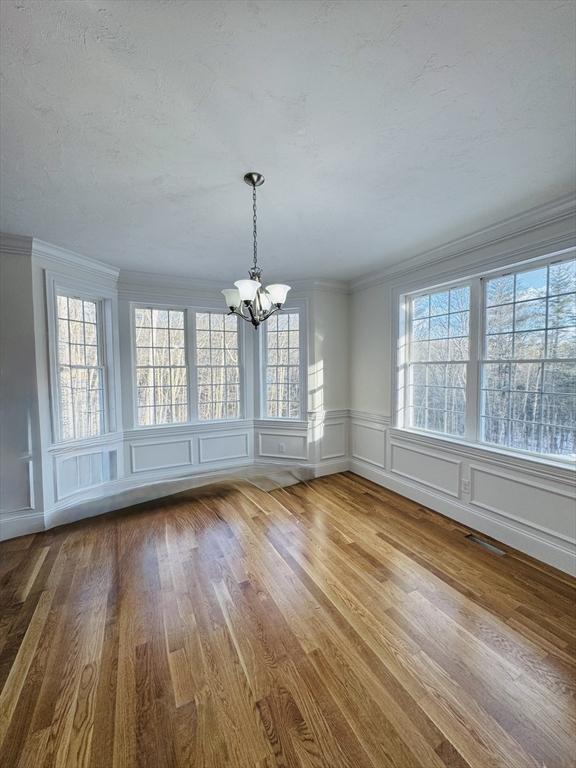 200A Randall Rd, Berlin, MA 01503 - unfurnished dining area featuring a chandelier, a decorative wall, wood finished floors, ornamental molding, and healthy amount of natural light