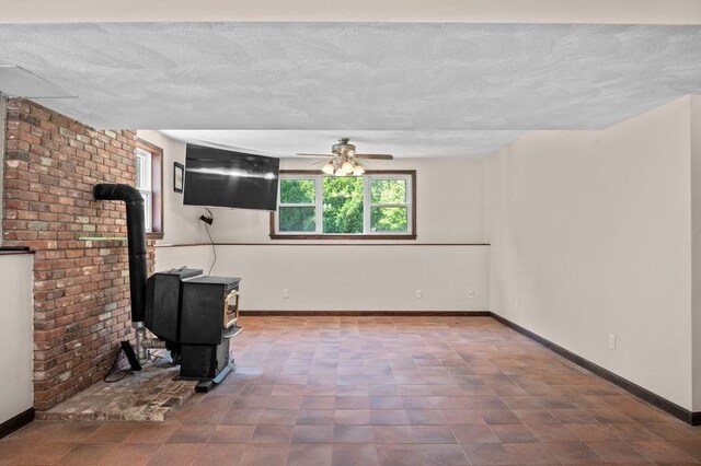 6 Myers Ln, Newbury, MA 01922 - unfurnished living room featuring plenty of natural light, a ceiling fan, baseboards, a textured ceiling, and a wood stove