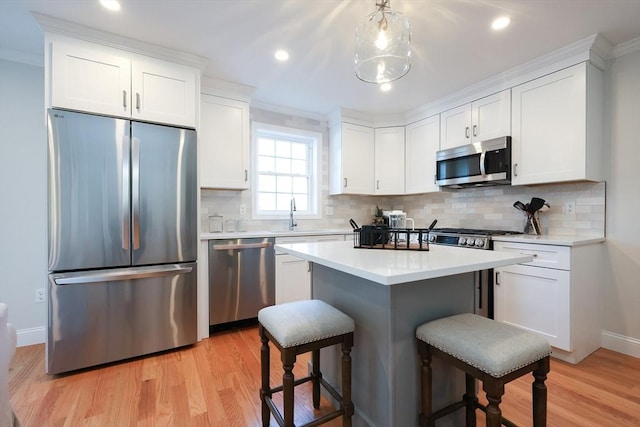 kitchen with light hardwood / wood-style flooring, appliances with stainless steel finishes, a kitchen breakfast bar, tasteful backsplash, and white cabinets