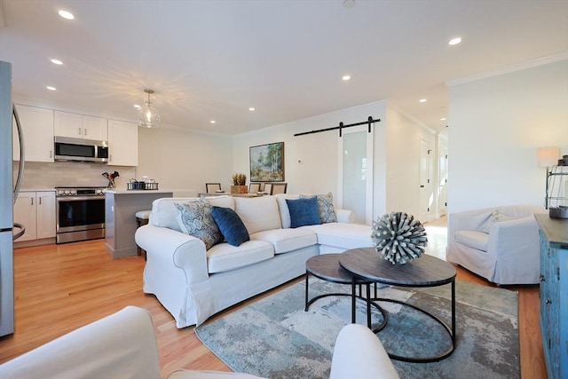 living room with ornamental molding, a barn door, and light wood-type flooring