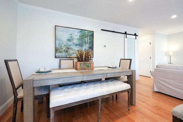 dining area with hardwood / wood-style flooring, ornamental molding, and a barn door