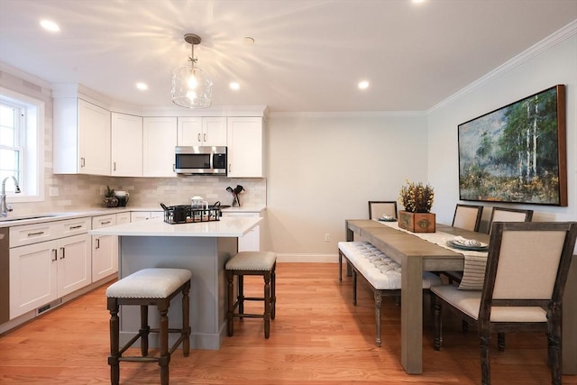 kitchen featuring white cabinetry, a center island, sink, and hanging light fixtures