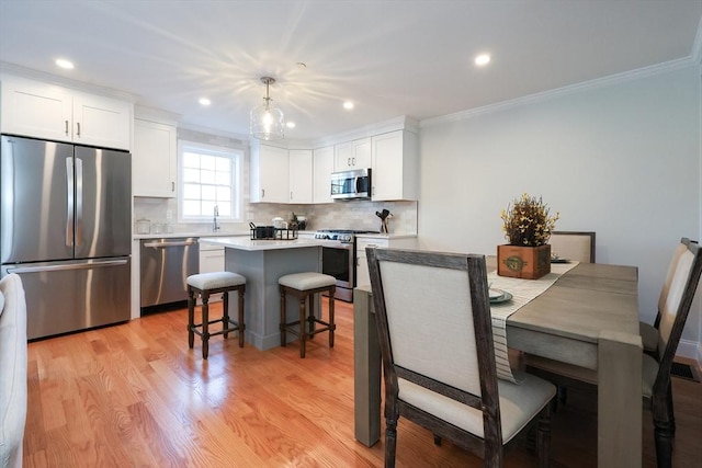 dining space with sink, crown molding, and light wood-type flooring