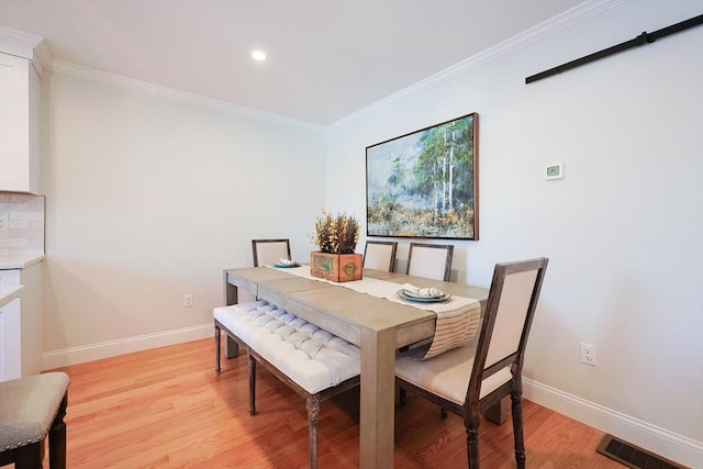 dining space with ornamental molding and light wood-type flooring