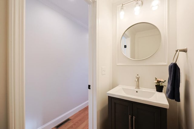 bathroom with vanity, crown molding, and hardwood / wood-style flooring