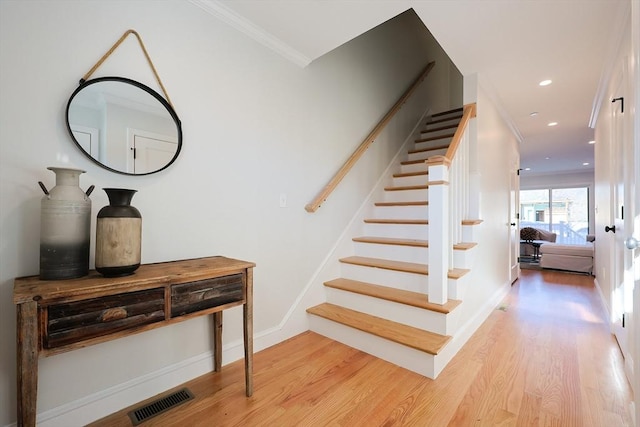 stairs with crown molding and hardwood / wood-style flooring