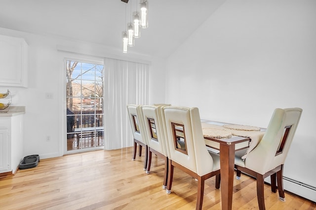 dining room with vaulted ceiling, light hardwood / wood-style flooring, and baseboard heating