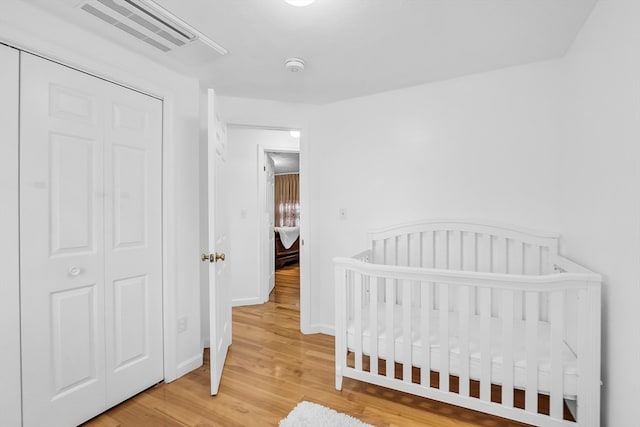 bedroom featuring a closet, a crib, and hardwood / wood-style flooring