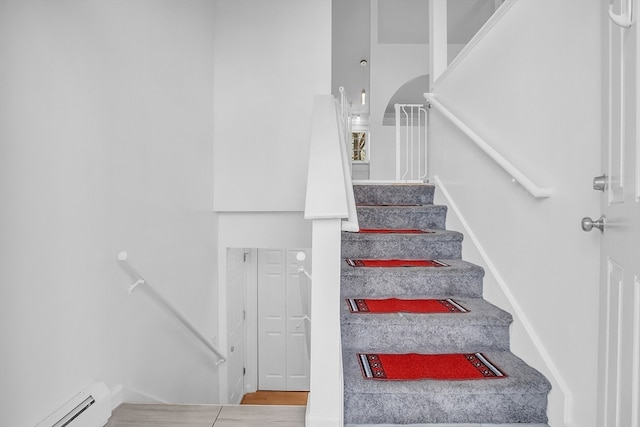 stairs featuring hardwood / wood-style floors and a baseboard radiator