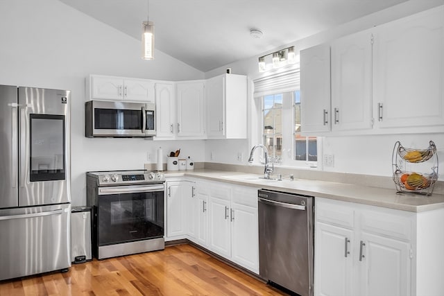 kitchen with white cabinets, stainless steel appliances, and lofted ceiling