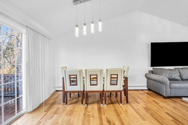 dining room with light hardwood / wood-style floors, lofted ceiling, and a baseboard heating unit