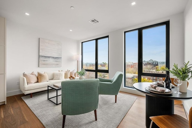 living area featuring wood finished floors, recessed lighting, a city view, and baseboards