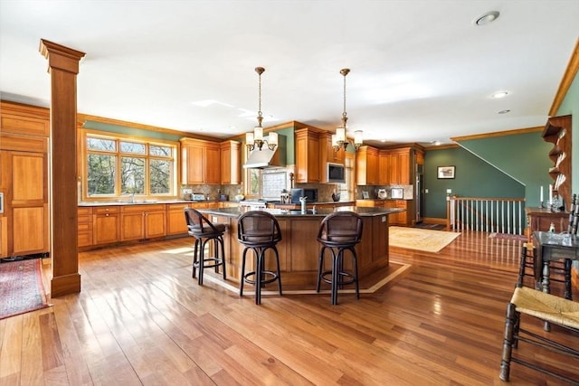45 Joshua Rd, Wrentham, MA 02093 - kitchen featuring custom range hood, backsplash, light wood-style flooring, a breakfast bar, and crown molding