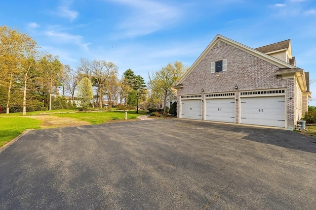45 Joshua Rd, Wrentham, MA 02093 - view of side of home with asphalt driveway, brick siding, a garage, and a lawn