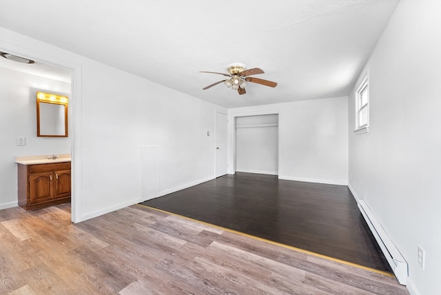 empty room featuring sink, ceiling fan, light hardwood / wood-style flooring, and baseboard heating