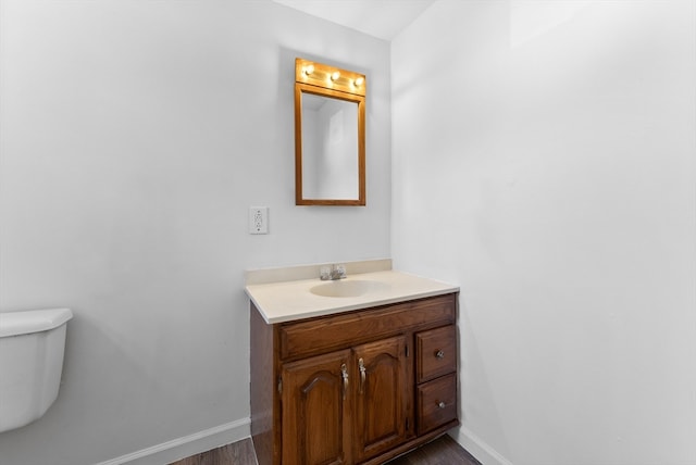 bathroom with toilet, vanity, and wood-type flooring