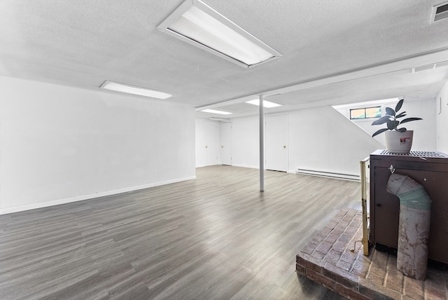 basement featuring a textured ceiling, a baseboard radiator, and dark hardwood / wood-style flooring